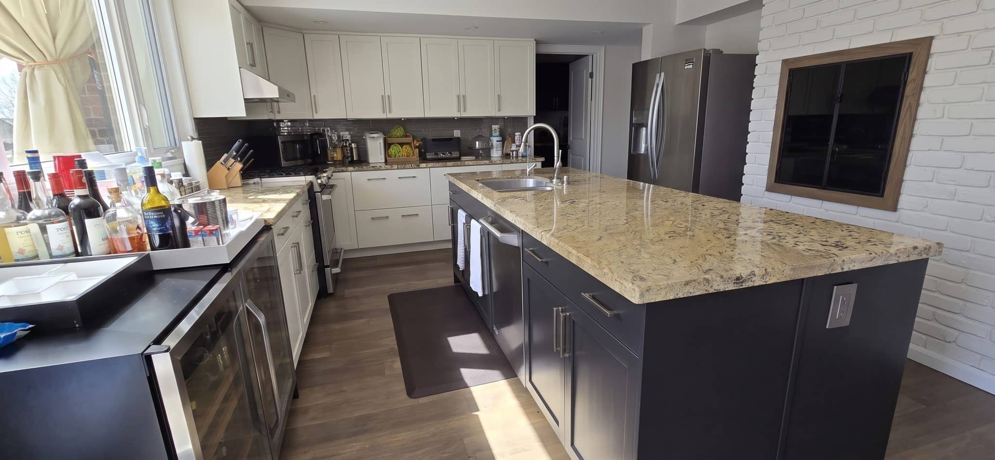Same kitchen after Arsh Art refinishing: white perimeter cabinets and a dark painted island